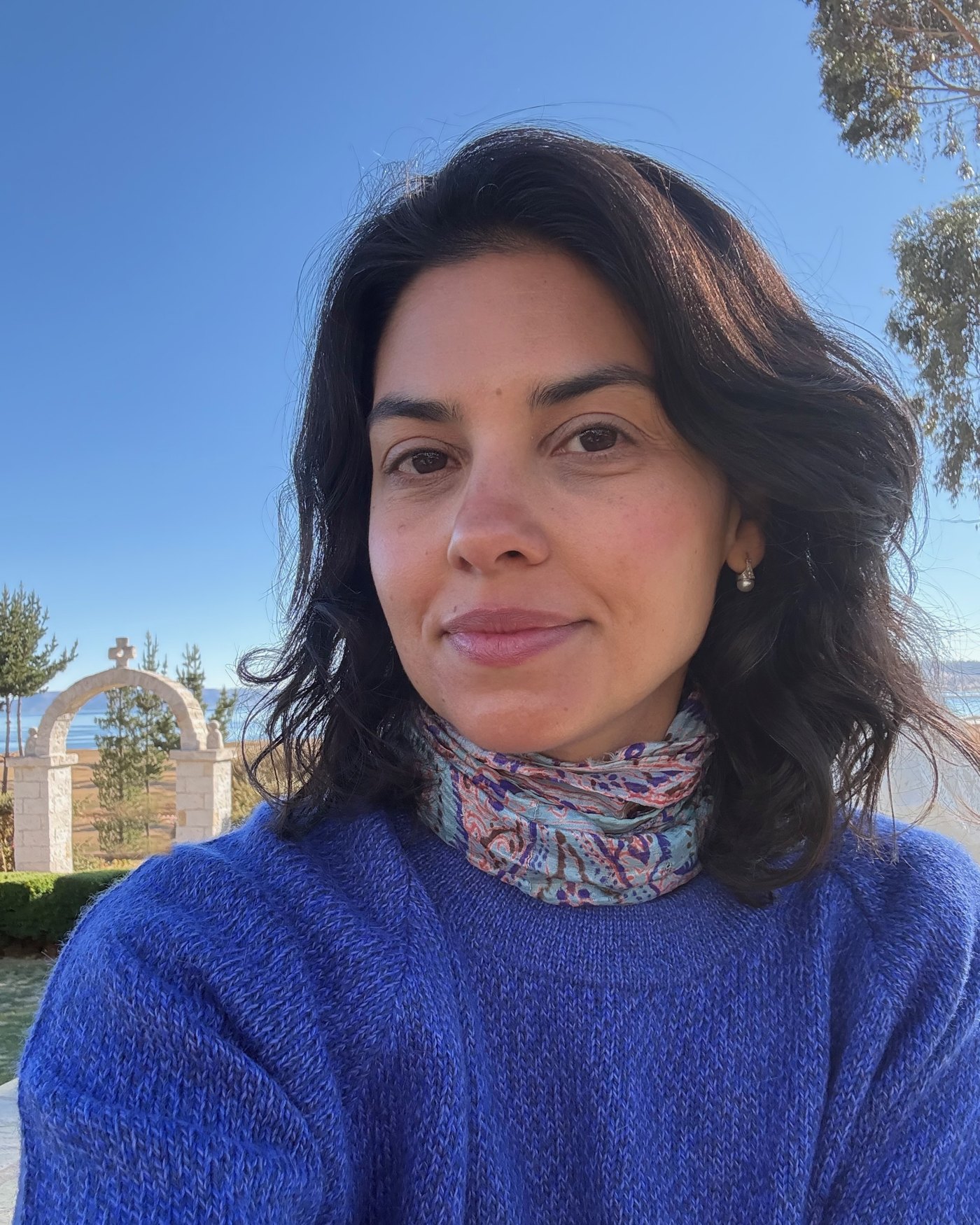 Alice Chaves, com o Lago Titicaca e um portal com a chakana ao fundo
